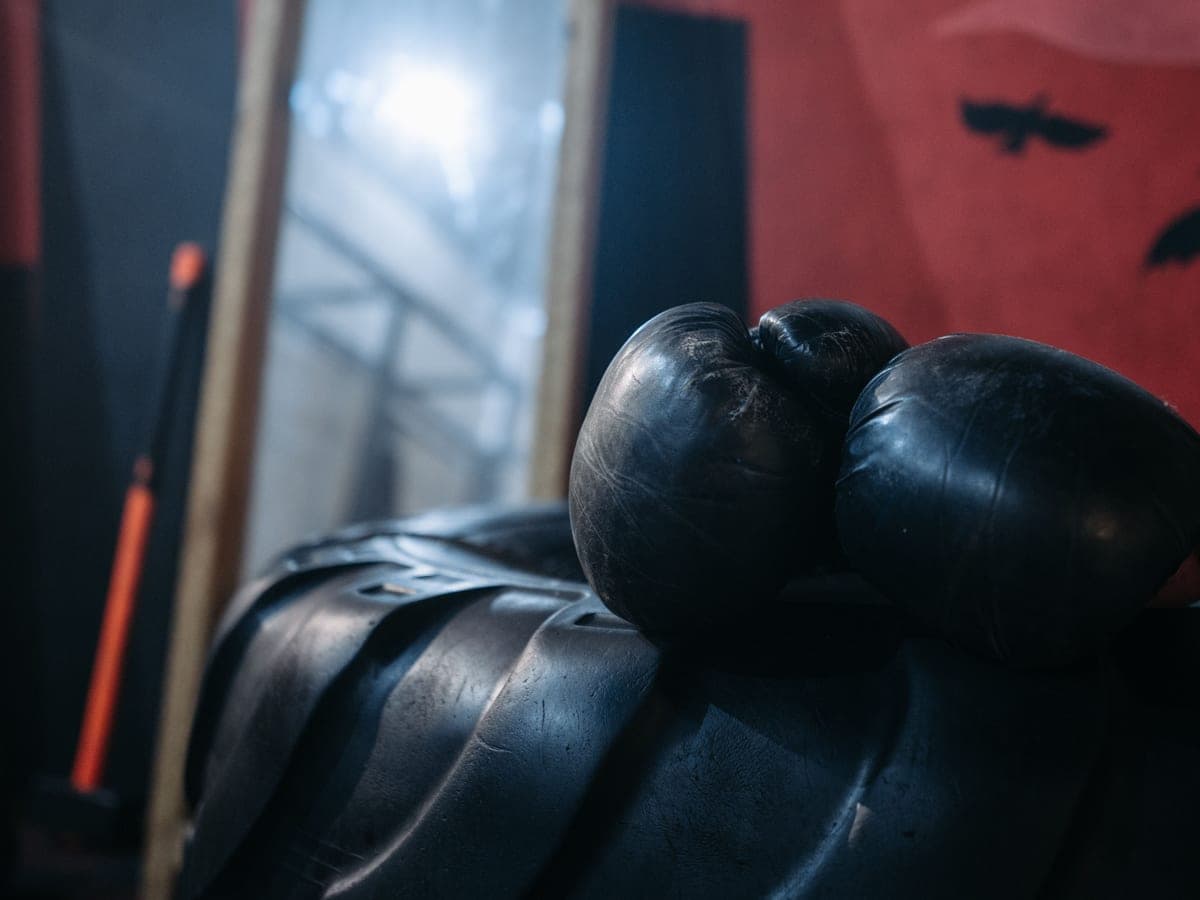 A pair of black boxing gloves resting on a bench in a gym — Bag & Bell, boxing & combat sports gear