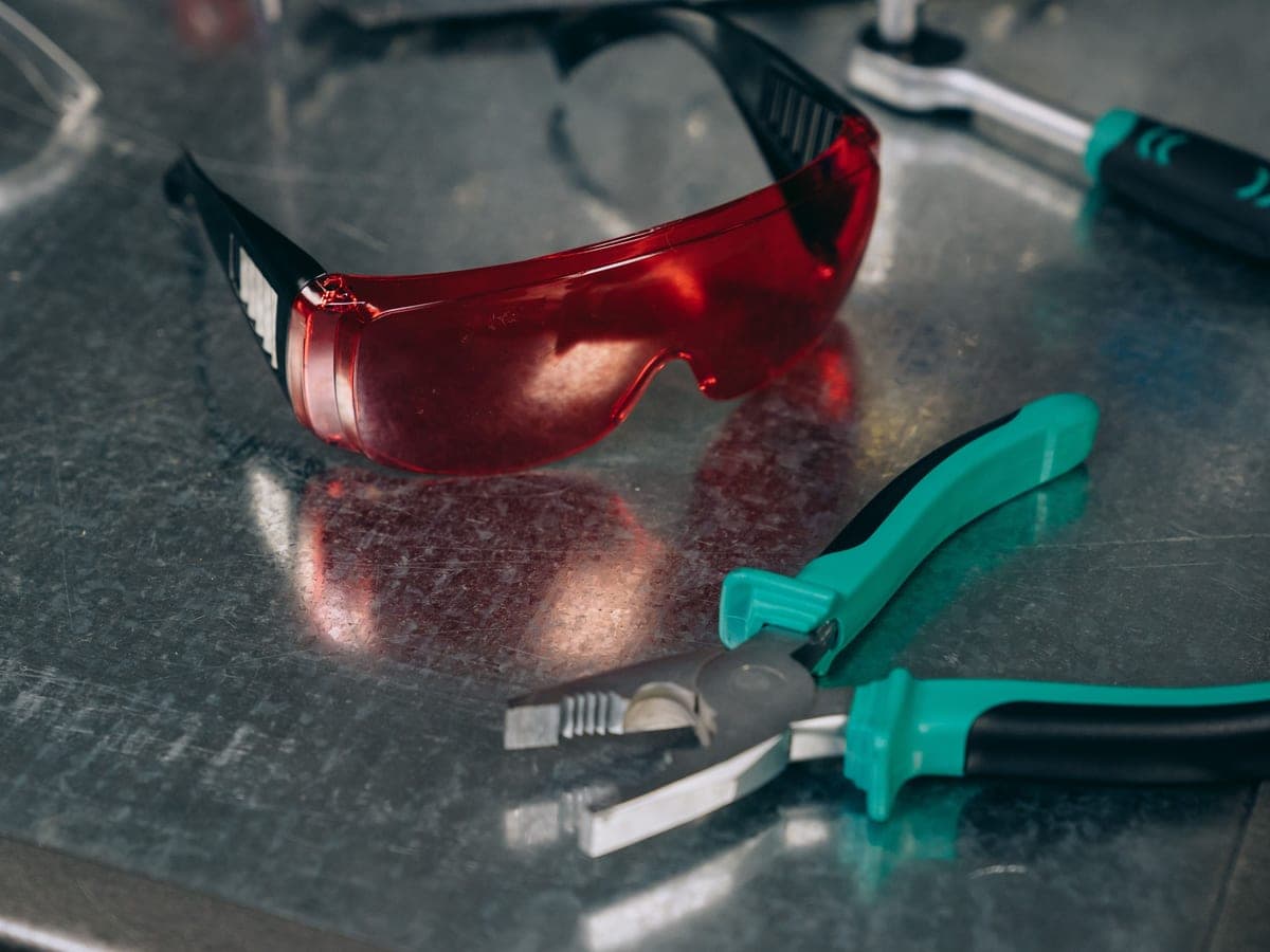 Safety glasses and work gloves on a workshop bench — Lens & Lead, shooting & safety eyewear