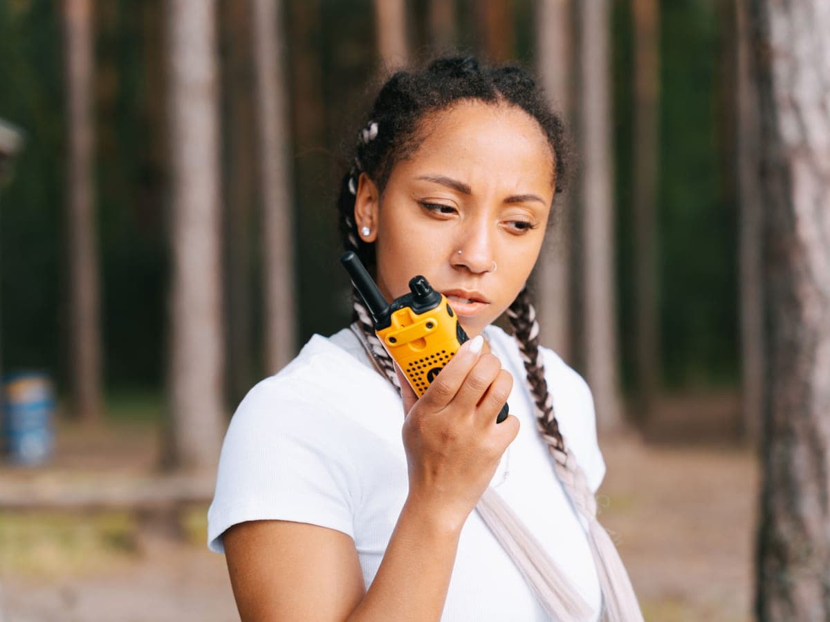 A woman speaking into a handheld two-way radio in the woods — Radio & Range, walkie-talkies, gmrs & two-way radios