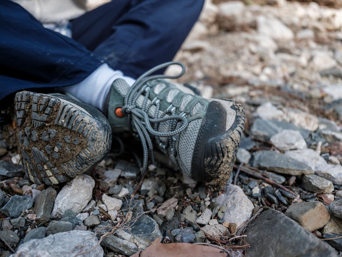 Worn hiking boots on a rocky riverbed — Sole & Summit, hiking boots & trail footwear